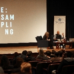 Three individuals sitting in front of projector screen saying SAMPLING